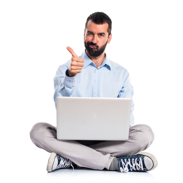 Hombre con la computadora portátil con el pulgar para arriba