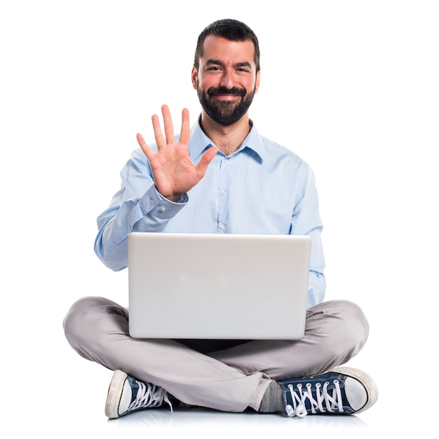 Hombre con la computadora portátil que cuenta cinco