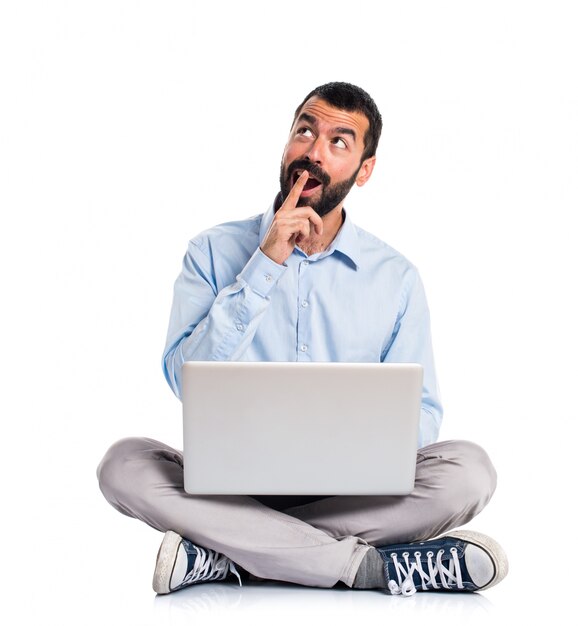 Hombre con la computadora portátil que hace gesto de la sorpresa