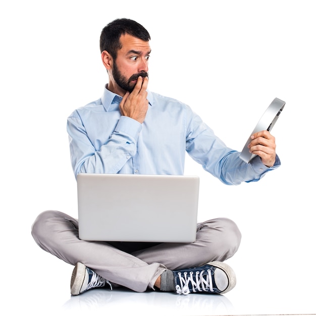 Hombre con la computadora portátil que sostiene un reloj