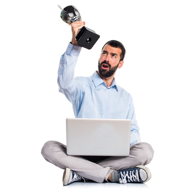 Hombre con la computadora portátil que sostiene un trofeo