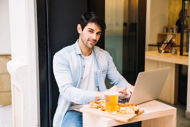 Hombre con computadora portátil relajante en café