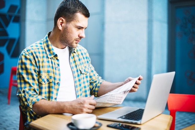 Foto gratuita hombre concentrado leyendo noticias en la mesa