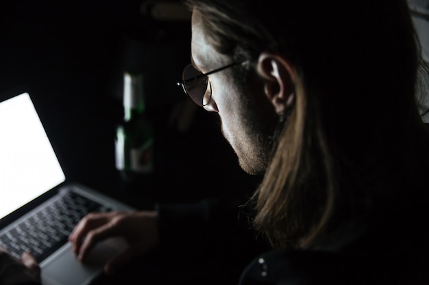 Hombre concentrado usando la computadora portátil en casa en el interior