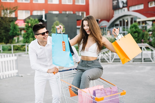 Hombre conduciendo carrito de compras con su novia