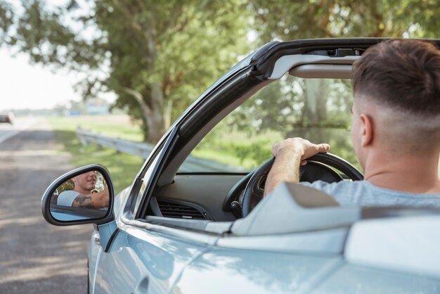 Hombre conduciendo un coche en la naturaleza