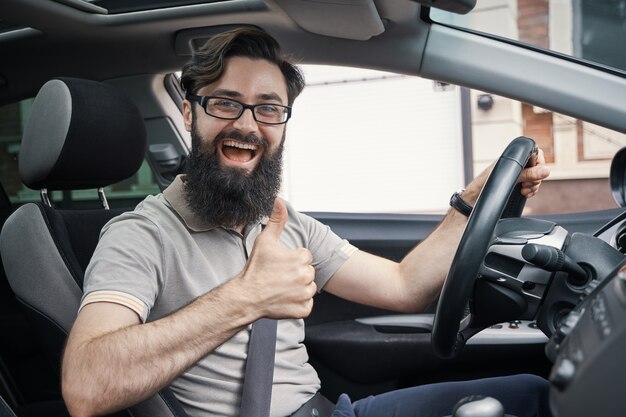 Hombre conductor feliz sonriendo mostrando los pulgares arriba conducir coche deportivo