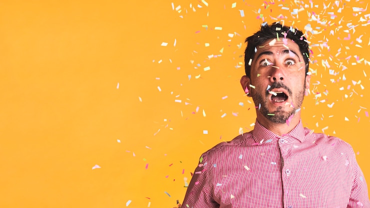 Foto gratuito hombre y confeti sobre fondo naranja con espacio de copia
