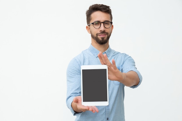 Hombre confiado que muestra la tableta digital con pantalla en blanco