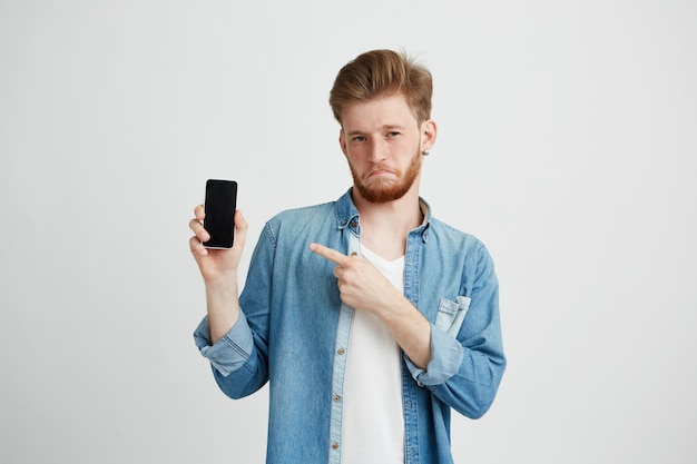 Hombre confidente hermoso joven que señala el dedo en el teléfono en su mano.