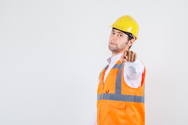 Hombre constructor en camisa, dedo acusador uniforme y mirando confiado, vista frontal.