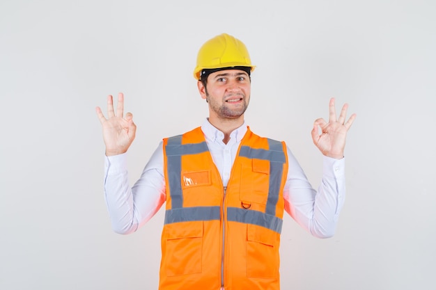 Hombre constructor haciendo gesto bien en camisa, uniforme y con aspecto positivo. vista frontal.