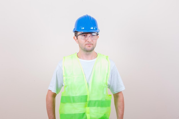 Hombre constructor mirando a otro lado en camiseta, casco y mirando sensato