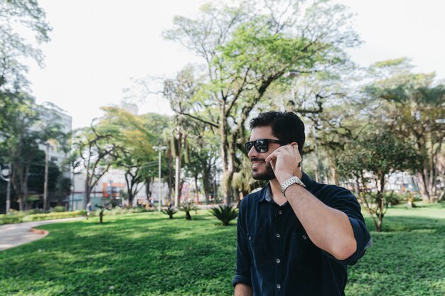 Hombre contenido que tiene llamada telefónica en el parque