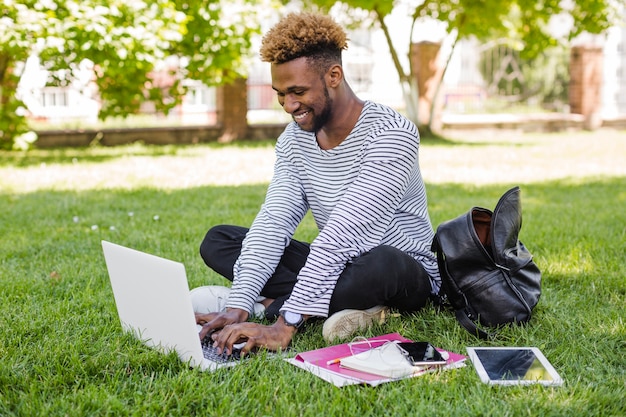 Hombre de contenido que usa la computadora portátil en césped