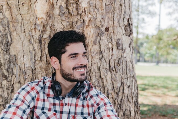 Hombre contento en auriculares relajantes en el parque