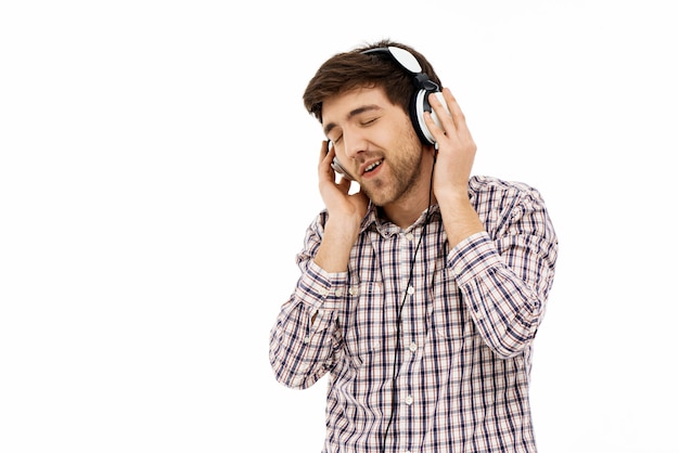 Hombre contento escuchando música en auriculares, sonríe