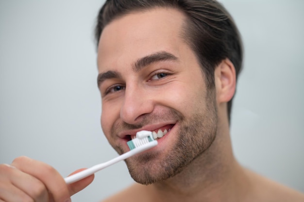 Hombre contento sonriente cepillándose los dientes