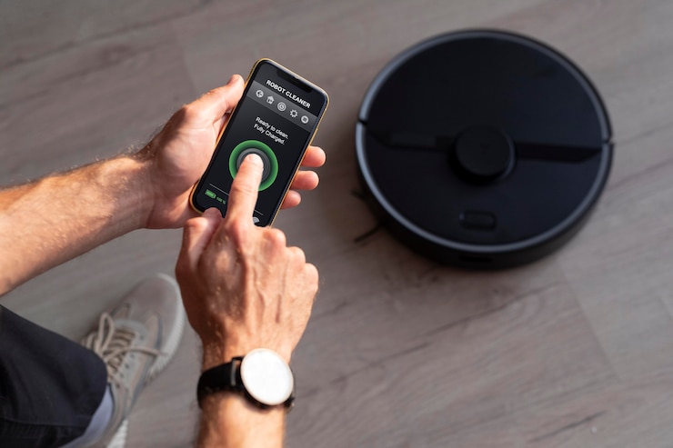 Foto gratuito hombre controlando un robot aspirador con su teléfono