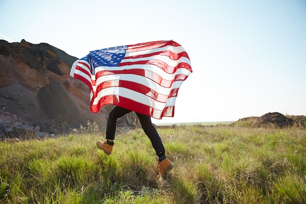 Hombre corriendo con bandera de Estados Unidos en la naturaleza