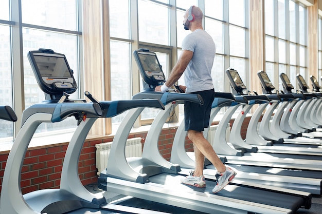 Hombre corriendo en la caminadora en el gimnasio moderno