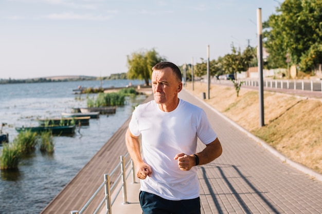 Hombre corriendo por el lago tiro medio