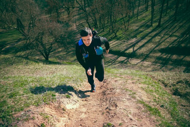 Hombre corriendo en un parque o bosque contra árboles