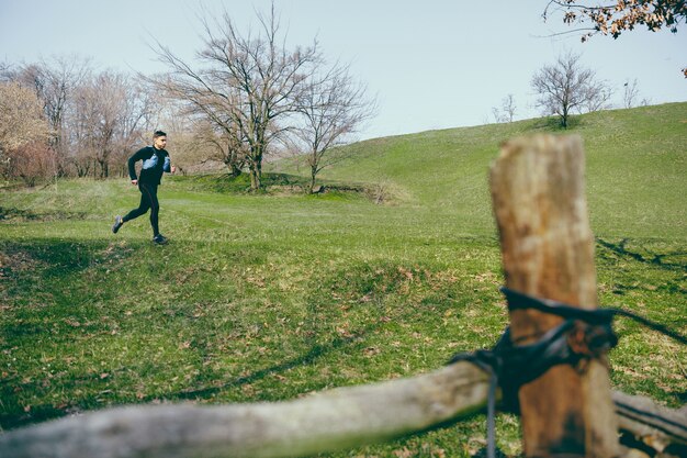 Hombre corriendo en un parque o bosque contra árboles