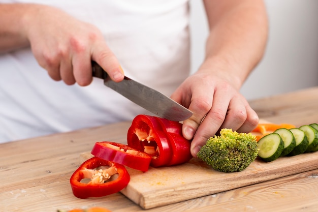 Hombre cortando verduras en una bandeja de madera