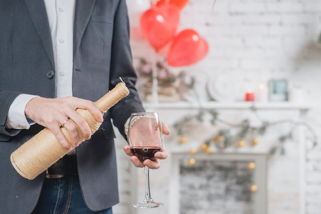 Hombre de la cosecha que vierte el vino rojo en vidrio