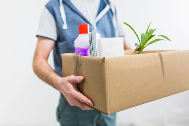 Hombre cosecha sosteniendo caja con pertenencias