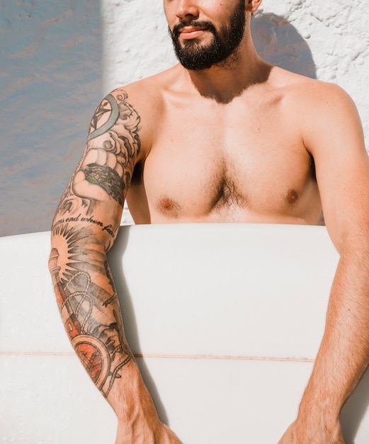 Hombre de la cosecha con el tatuaje con tabla de surf