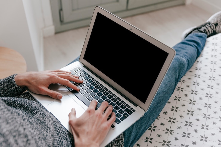 Foto gratuito hombre de cosecha usando la computadora portátil en la cama