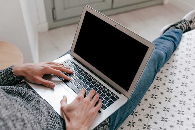 Hombre de cosecha usando la computadora portátil en la cama