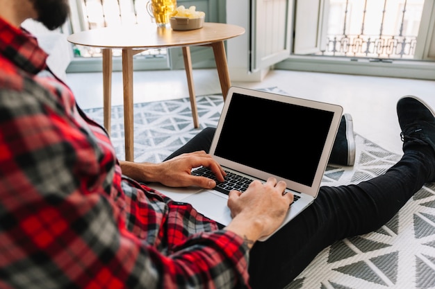 Hombre de cosecha usando la computadora portátil en el piso