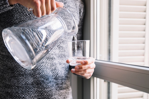 Foto gratuita hombre cosecha verter agua cerca de la ventana