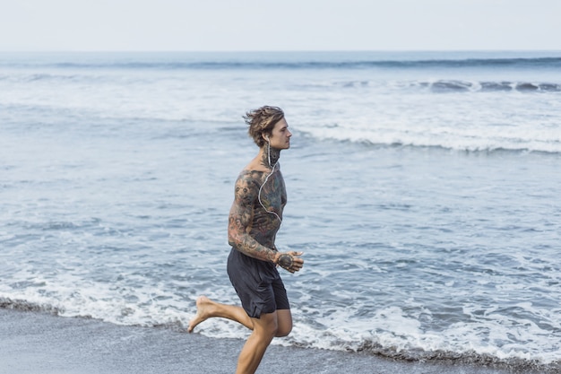 un hombre en la costa del océano corriendo a lo largo de la orilla del mar