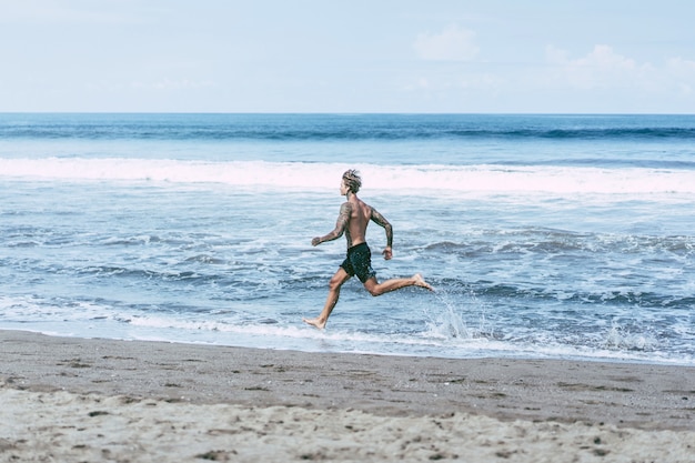 un hombre en la costa del océano corriendo a lo largo de la orilla del mar