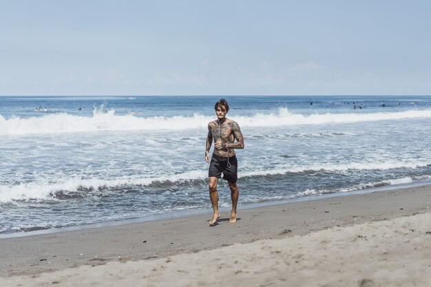 un hombre en la costa del océano corriendo a lo largo de la orilla del mar