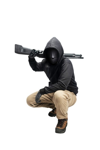 Hombre criminal en una máscara oculta sentado y sosteniendo la escopeta aislado sobre fondo blanco.