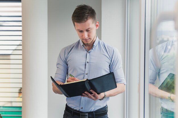 Hombre con el cuaderno que presenta en oficina