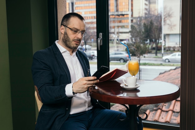 Hombre con el cuaderno que usa el teléfono inteligente