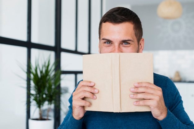 Foto gratuita hombre cubriéndose la cara con un libro en casa