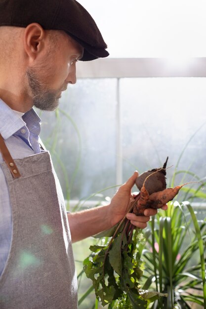 Hombre cultivando verduras en su jardín interior