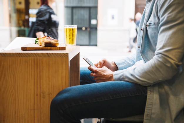 Foto gratuita hombre de cultivo con teléfono inteligente en el restaurante