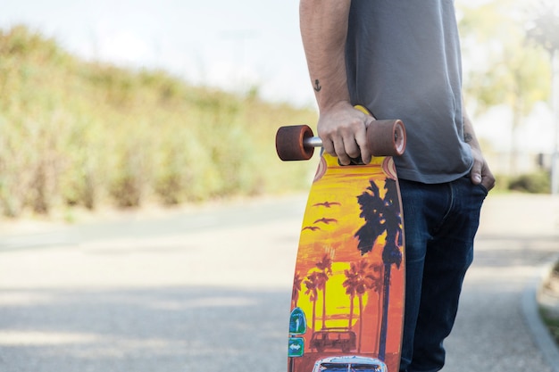 Hombre de cultivos apoyándose en longboard