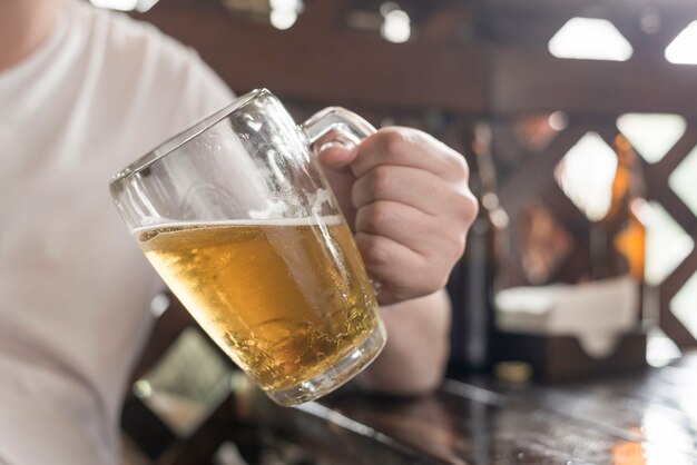 Hombre de cultivos con cerveza apoyándose en la mesa