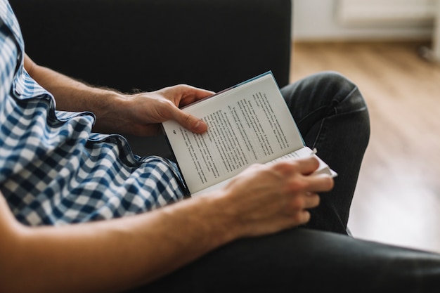 Hombre de cultivos disfrutando de la lectura en el sofá