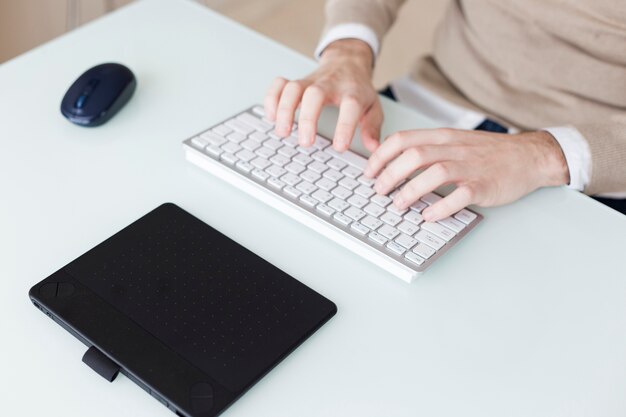 Hombre de cultivos escribiendo en un teclado pequeño