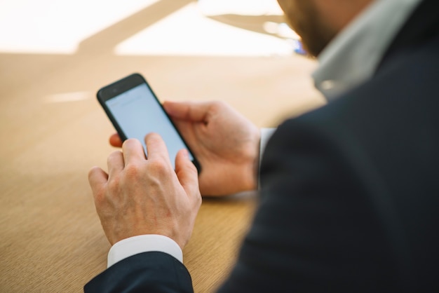 Hombre de cultivos con teléfono inteligente en la oficina